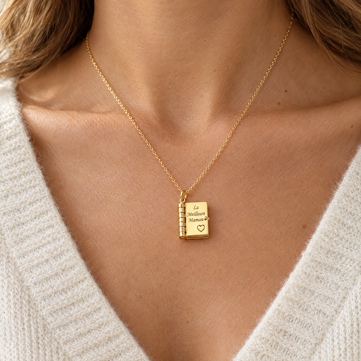 Collier livre doré La Meilleure Maman porté sur un pull crème